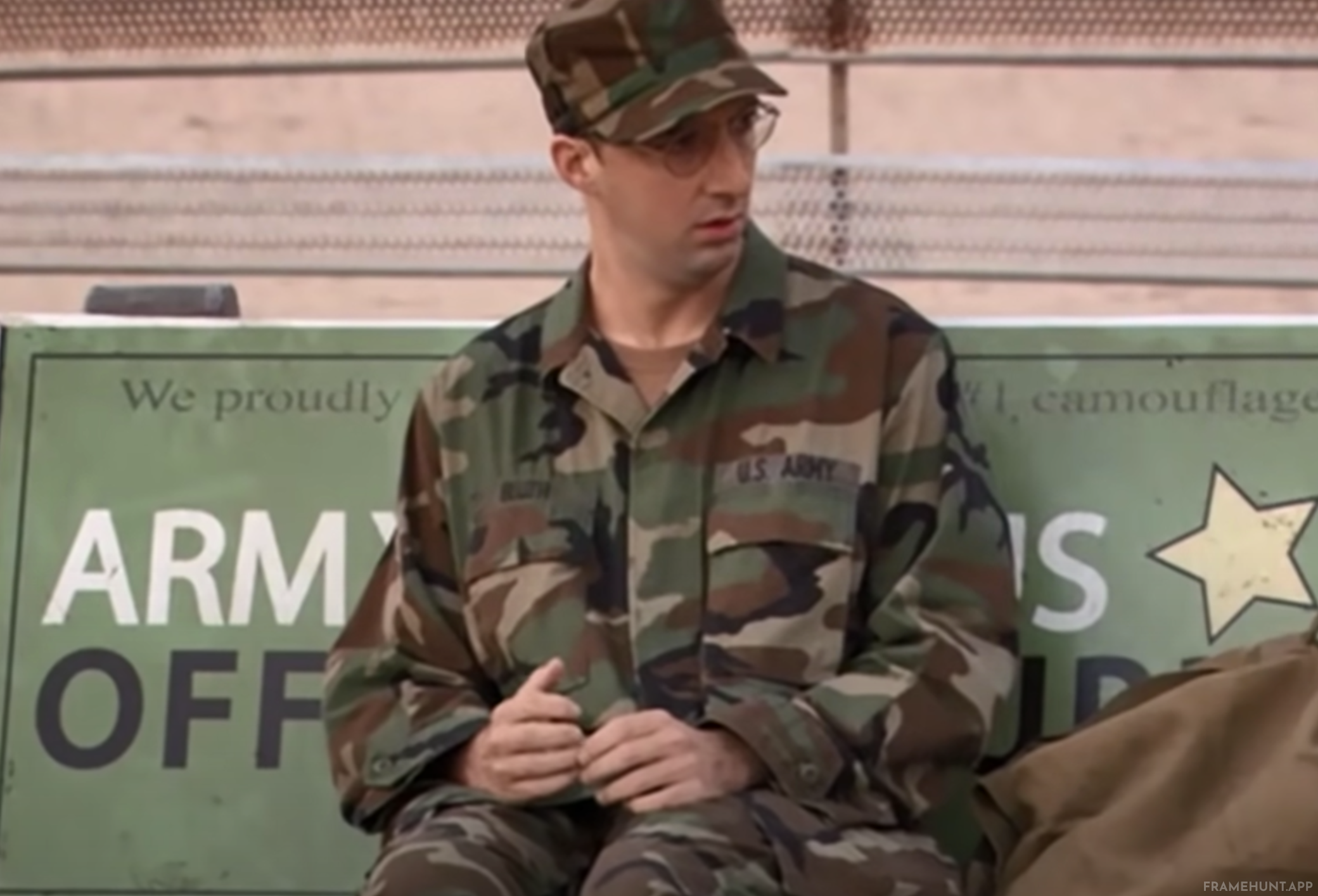 Buster sits perfectly positioned on an army bench so that the advertisement behind him ominously reads "ARM OFF". in Arrested Development