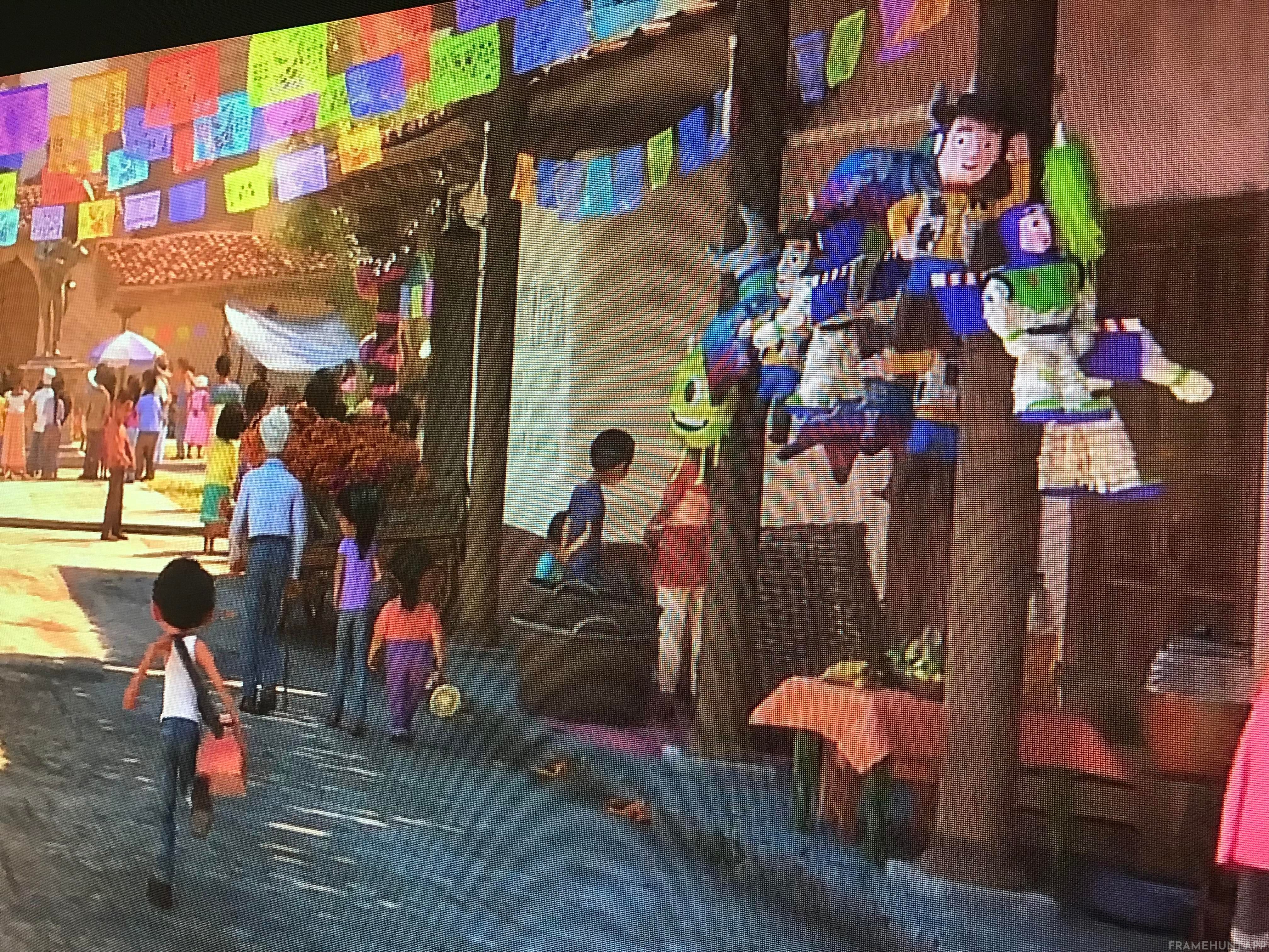 Piñatas shaped exactly like Buzz Lightyear, Woody, and Mike Wazowski are hanging in the background market. in Coco