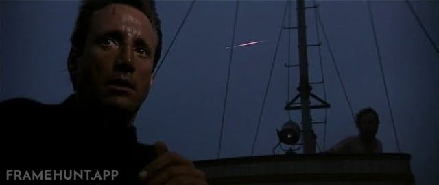 A massive, incredibly bright shooting star streaks across the dark night sky right behind Chief Brody. in Jaws
