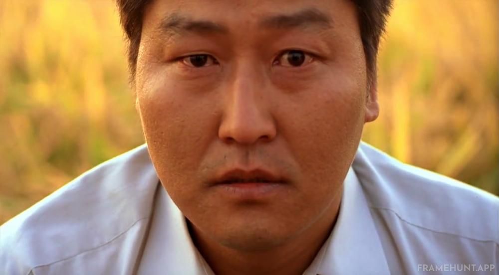 Song Kang-ho stares directly into the camera lens, looking straight at the audience. in Memories of Murder