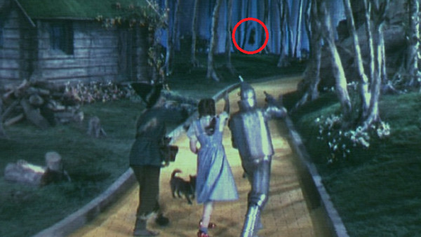 A dark figure is seen moving in the background of the forest, sparking a decades-long urban legend in The Wizard of Oz
