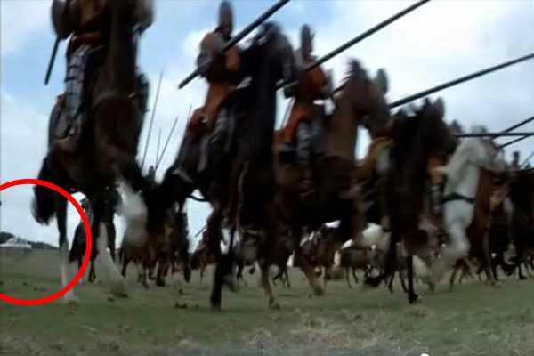 A modern white car is parked in the background during an intense 13th-century battle charge. in Braveheart