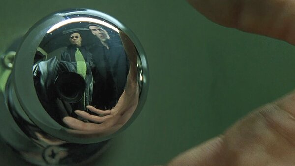 The camera lens and cameraman are fully visible in the reflection of a shiny doorknob. in The Matrix